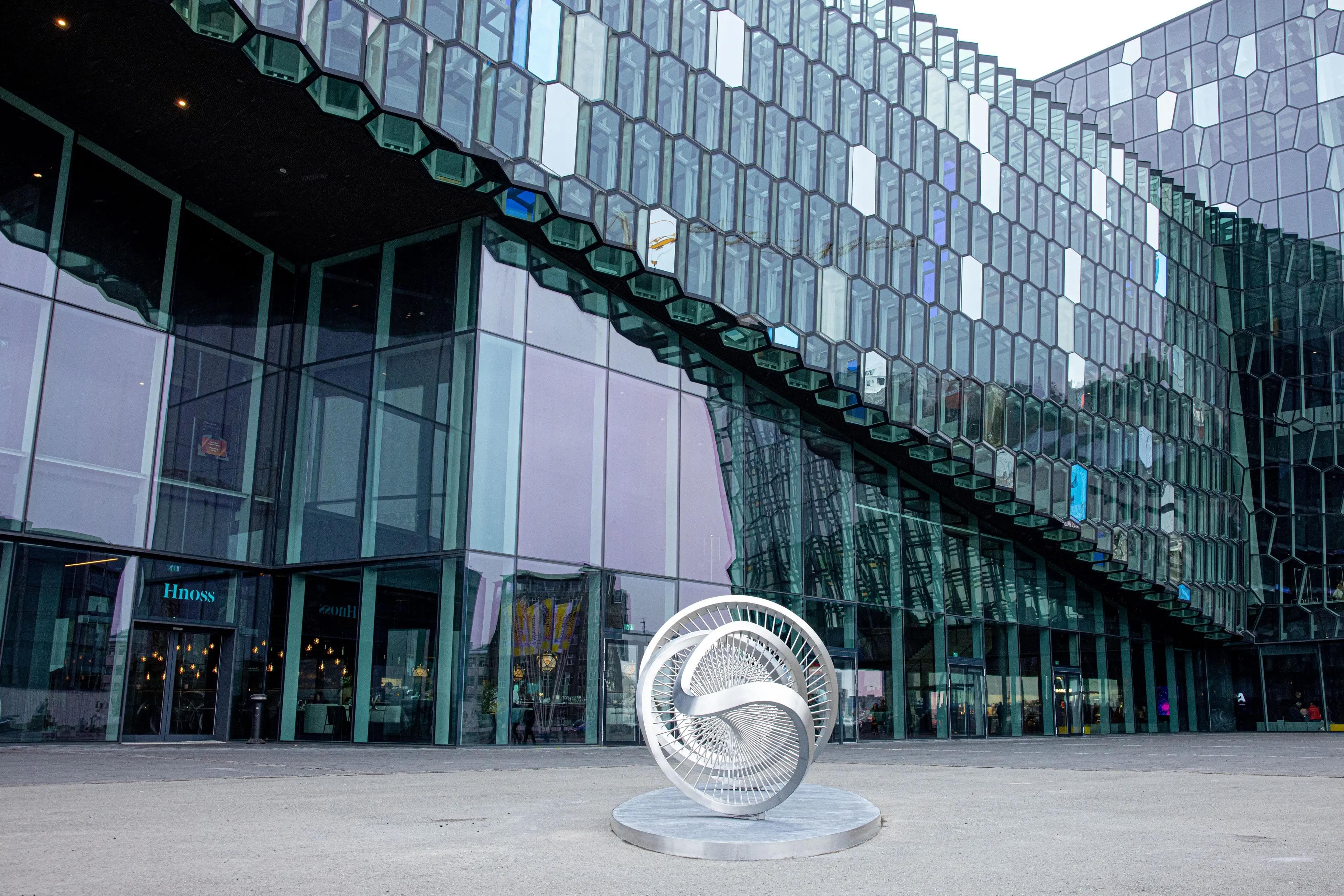 a large glass building with a sculpture in front of it .